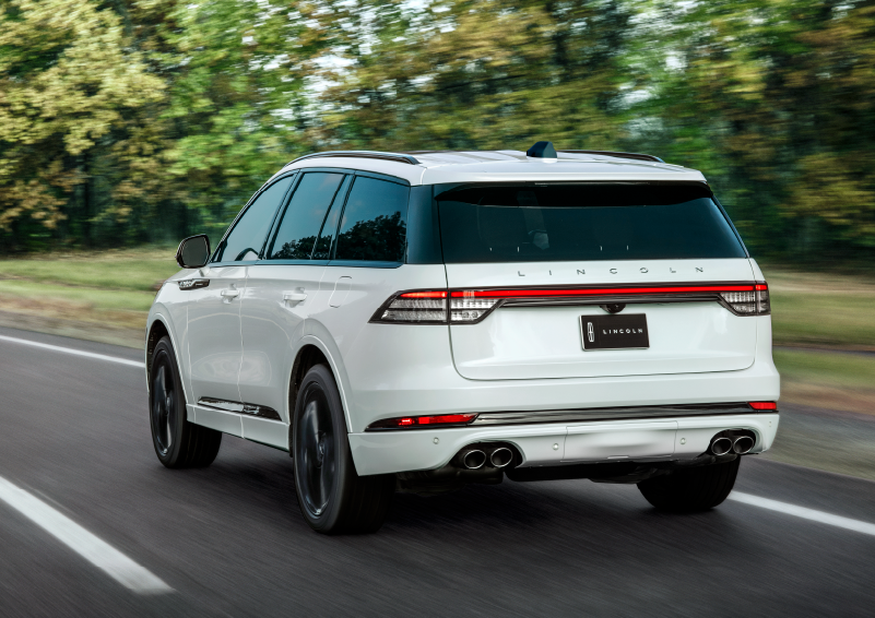 A white 2025 Lincoln Aviator® SUV is being driven away down a road lined with colorful trees. | Don Franklin Lincoln in London KY