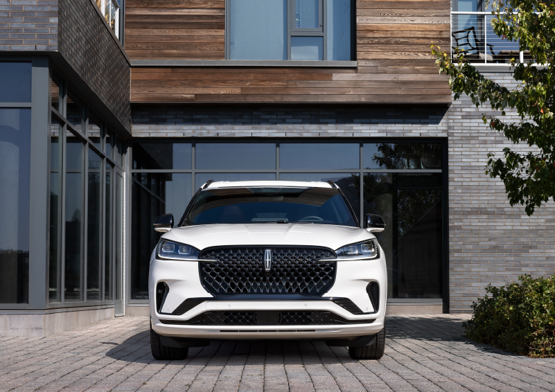 A white 2025 Lincoln Aviator® SUV is shown parked outside a modern building with gray brick and wood accents. | Don Franklin Lincoln in London KY