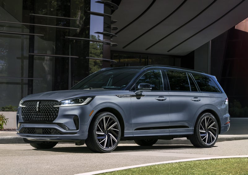 A gray 2025 Lincoln Aviator® SUV is parked outside a modern building showcasing the driver’s side of the vehicle. | Don Franklin Lincoln in London KY
