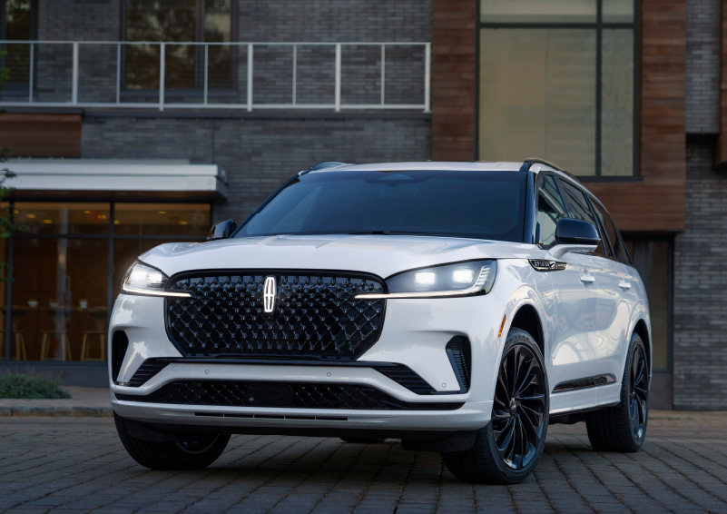 A white 2025 Lincoln Aviator® SUV is shown parked outside a modern building with gray brick and wood accents. | Don Franklin Lincoln in London KY