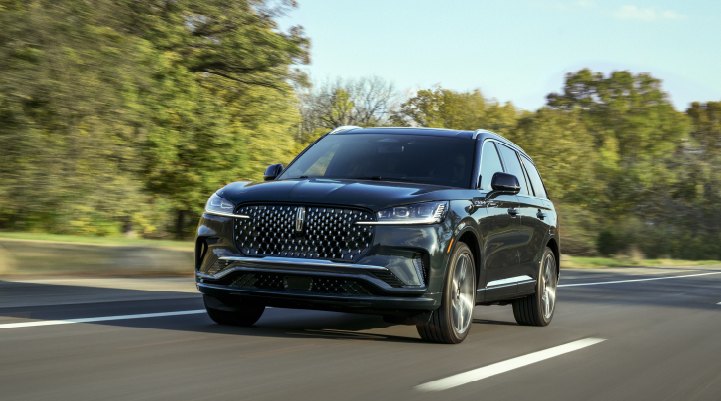 A 2025 Lincoln Black Label Aviator® SUV is being driven down a road lined with trees. | Don Franklin Lincoln in London KY
