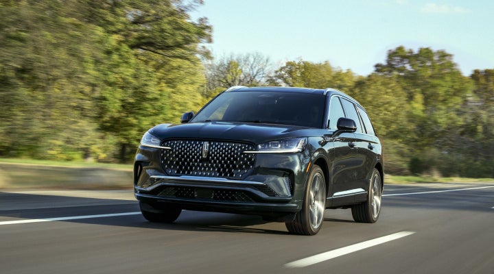 A 2026 Lincoln Black Label™ Aviator® SUV is being driven down a road lined with trees. | Don Franklin Lincoln in London KY