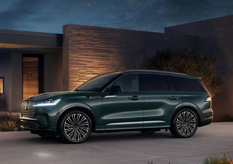 A green 2027 Lincoln Aviator® SUV is parked outside a contemporary home. | Don Franklin Lincoln in London KY