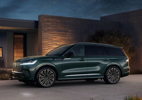 A green 2027 Lincoln Aviator® SUV is parked outside a contemporary home. | Don Franklin Lincoln in London KY