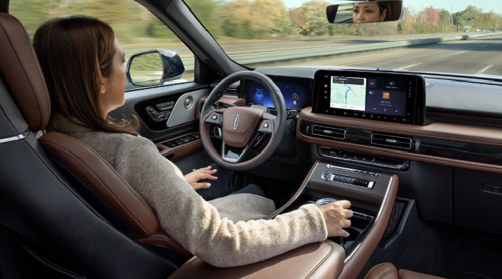 A 2027 Lincoln Aviator® SUV is being driven hands-free on a highway lined with trees. | Don Franklin Lincoln in London KY