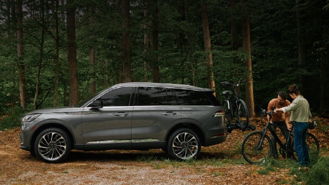 A father and son load e-bikes on a bike rack attached to a 2027 Lincoln Aviator® SUV. | Don Franklin Lincoln in London KY